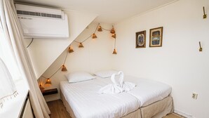 Un dormitorio con cama, lámpara colgante y dos cuadros en la pared.