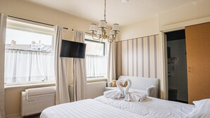 Habitación de hotel con cama, televisor, ducha y vistas a edificios.