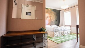Una camera da letto con un letto, una scrivania, uno specchio e un pannello di controllo a parete.