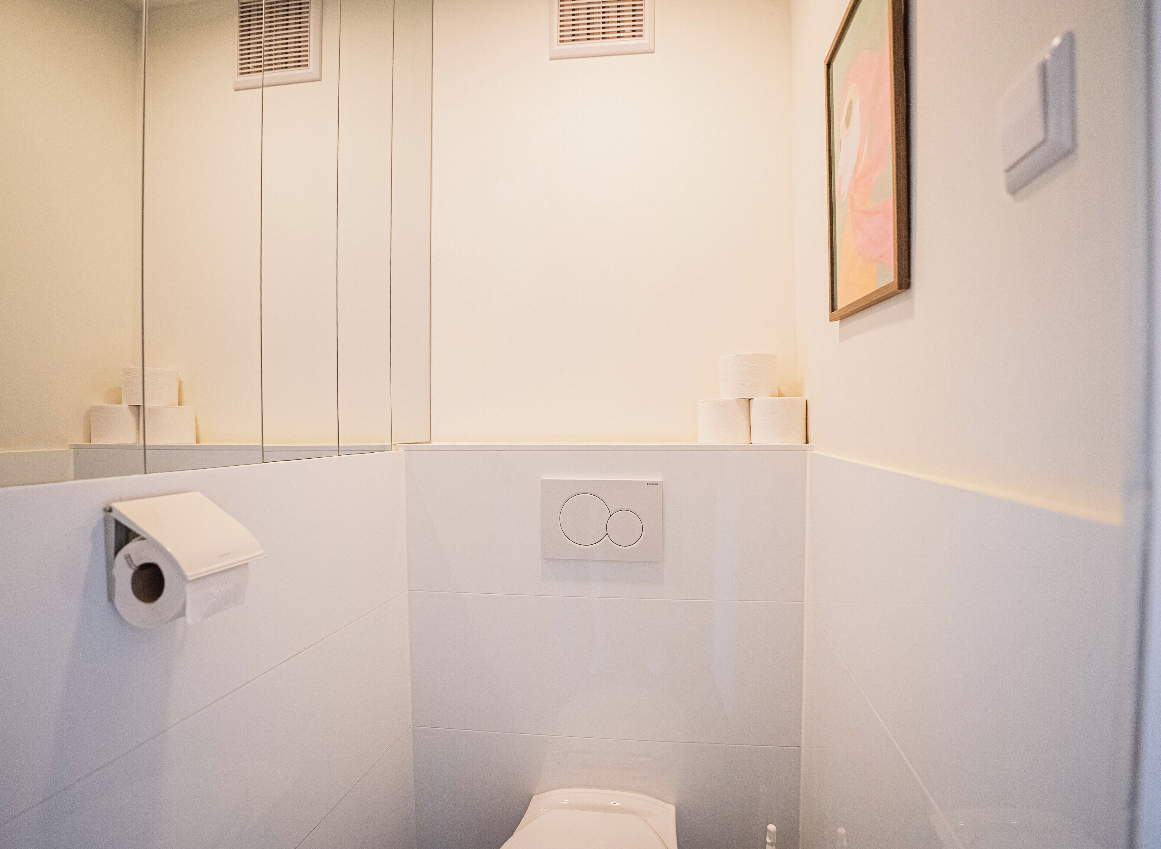 A modern bathroom with a toilet, a towel dispenser, and a toilet paper holder.