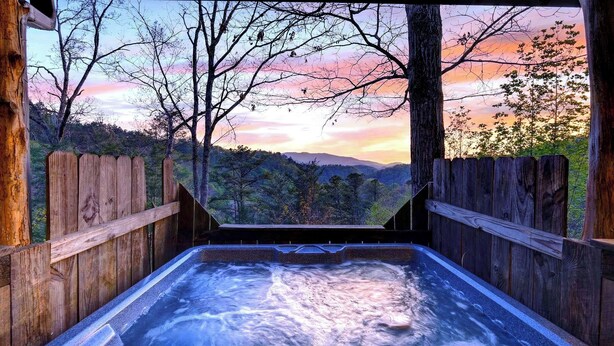 A hot tub with a view of a forested landscape during sunset. - Elijah's, Isaiah's, Jack's & Sónyah's Cabins by Avantstay 4 Hot Tubs + Firepit Mountain Views + Decks 9min to Great Smoky Mtns National Park (Townsend)