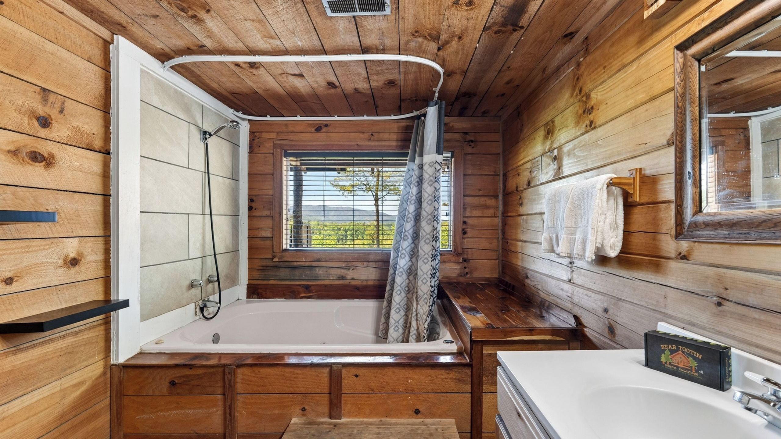 A wooden cabin bathroom with a bathtub, a shower, and a sink.