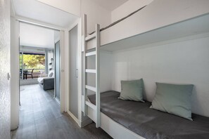 Un lit superposé avec deux oreillers, une porte coulissante et une vue sur un espace de détente extérieur.