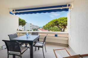 Un balcon avec une table et des chaises, une vue sur la mer et des bâtiments en arrière-plan.