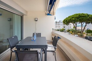 Un balcon avec une table et des chaises, une bouteille et un verre.