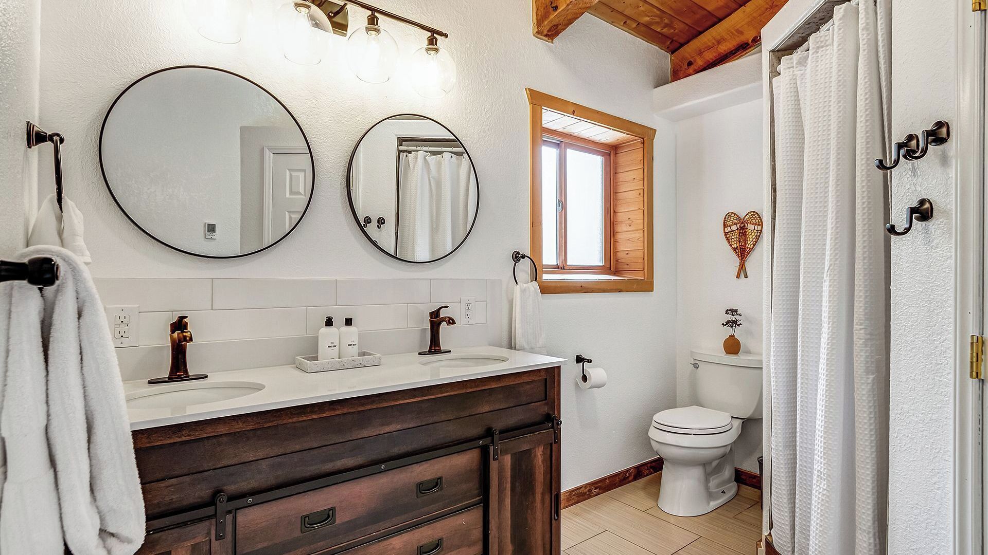 A bathroom with two sinks, a toilet, and a shower curtain.