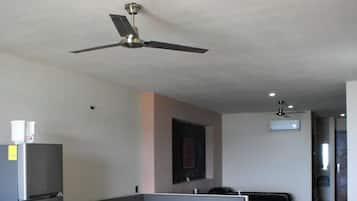 Una sala de estar moderna con un sofá empotrado, ventilador de techo y refrigerador.
