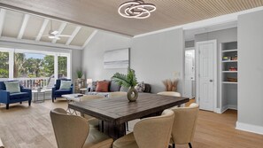 Un amplio salón con una mesa de comedor, sofás y vistas al exterior.