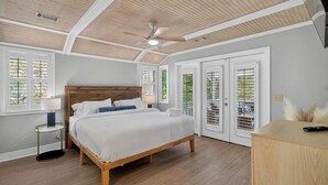 Un dormitorio con una cama de madera, un ventilador de techo y vistas a través de la ventana.
