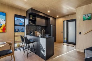 Eine moderne Küche mit Kochinsel, Barhocker und Essbereich mit Tisch und Stühlen.