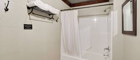 A bathroom with a bathtub, a shower curtain, a towel rack, and a sign indicating the use of a septic tank.