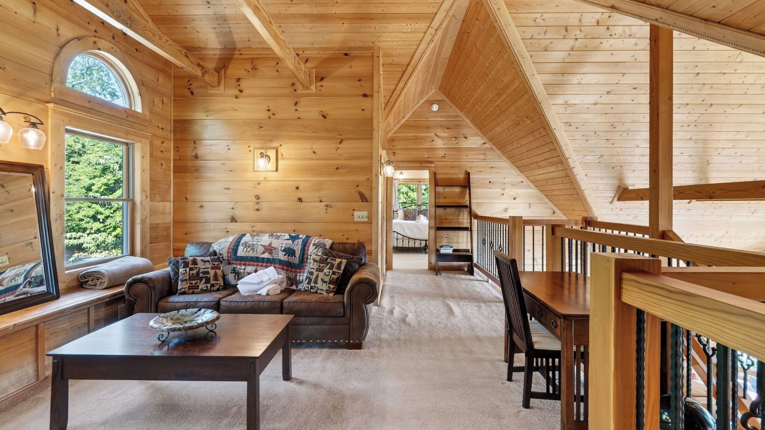 A log cabin interior with a sofa, table, and a view of the outdoors.