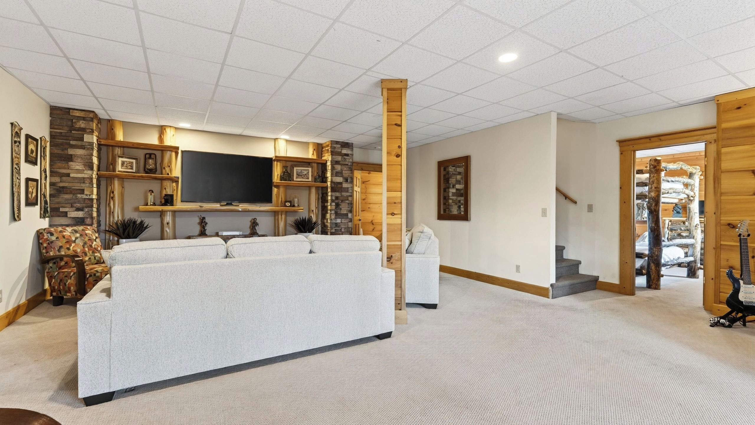 A spacious living room with a large flat-screen TV, a sofa, and a staircase leading to a loft area.