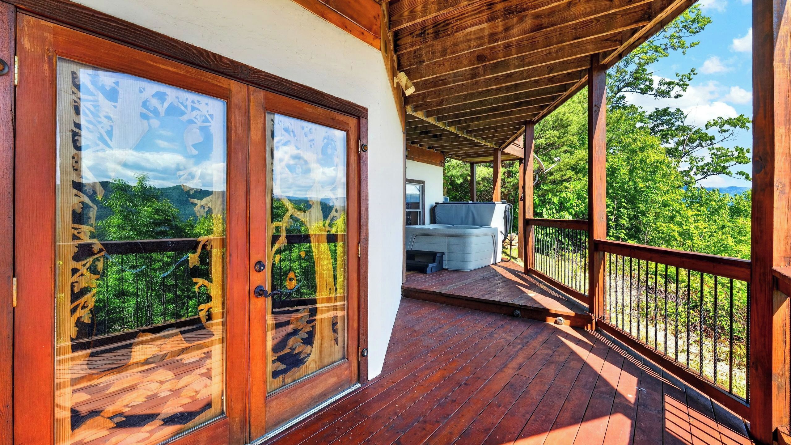 Une terrasse en bois avec une porte vitrée donnant sur une pièce, un barbecue et une vue sur la verdure.