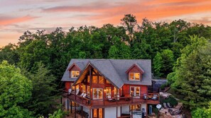 Ein zweigeschossiges Holzhaus mit Balkon, umgeben von dichtem Wald.