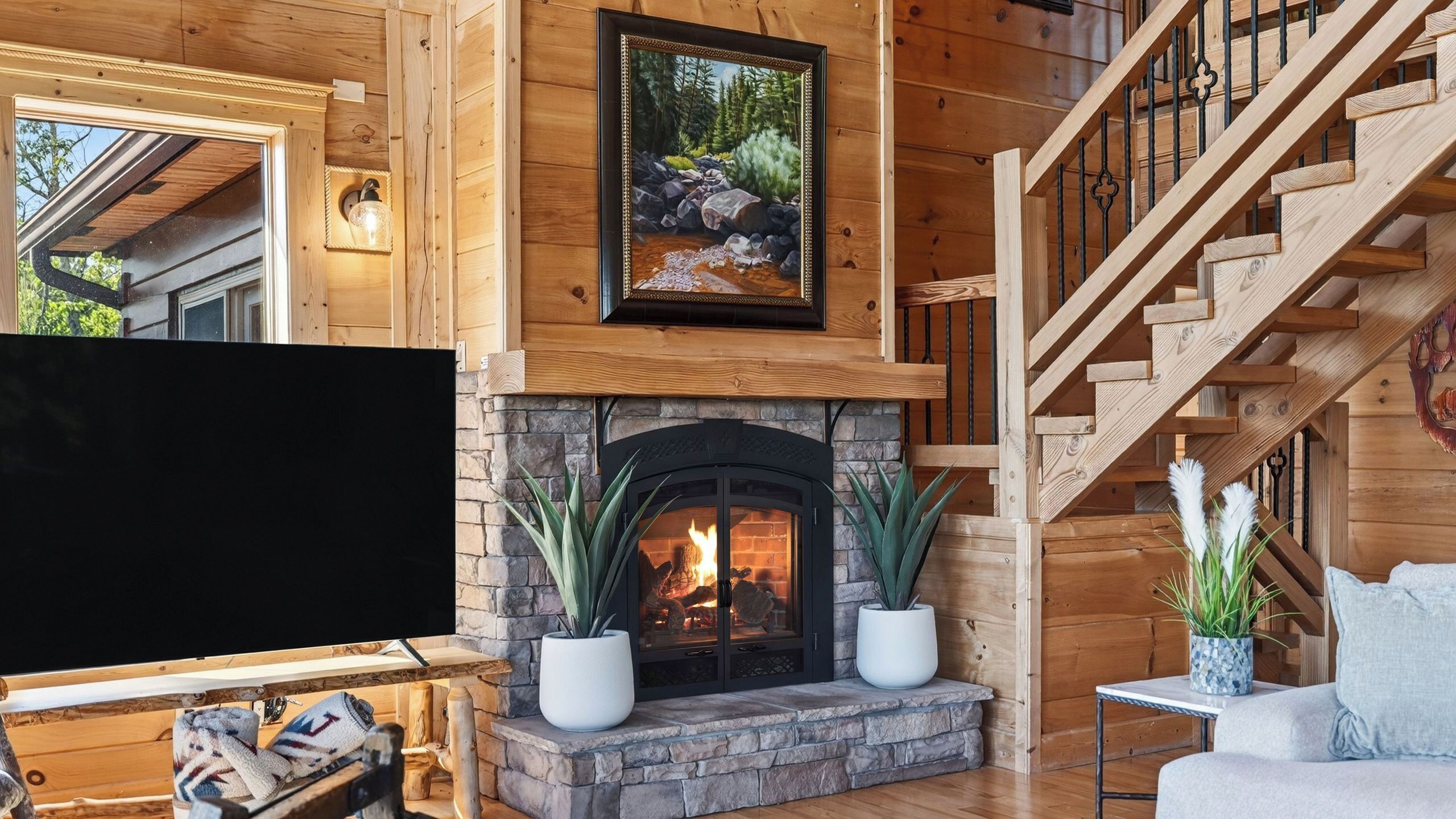 Un interior de madera con chimenea, una escalera y un televisor.
