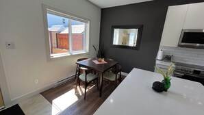 Une cuisine moderne avec un coin repas, une grande fenêtre et une vue sur le jardin arrière.