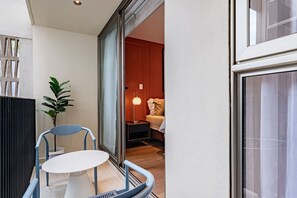 A balcony with a table and chairs, a potted plant, and a glimpse into the interior with a bed and lamp. - Condesa Apartment Near Parque México & España (Mexico City)