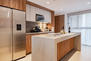 A modern kitchen with a built-in microwave, stainless steel refrigerator, and a central island. - Condesa Apartment Near Parque México & España (Mexico City)