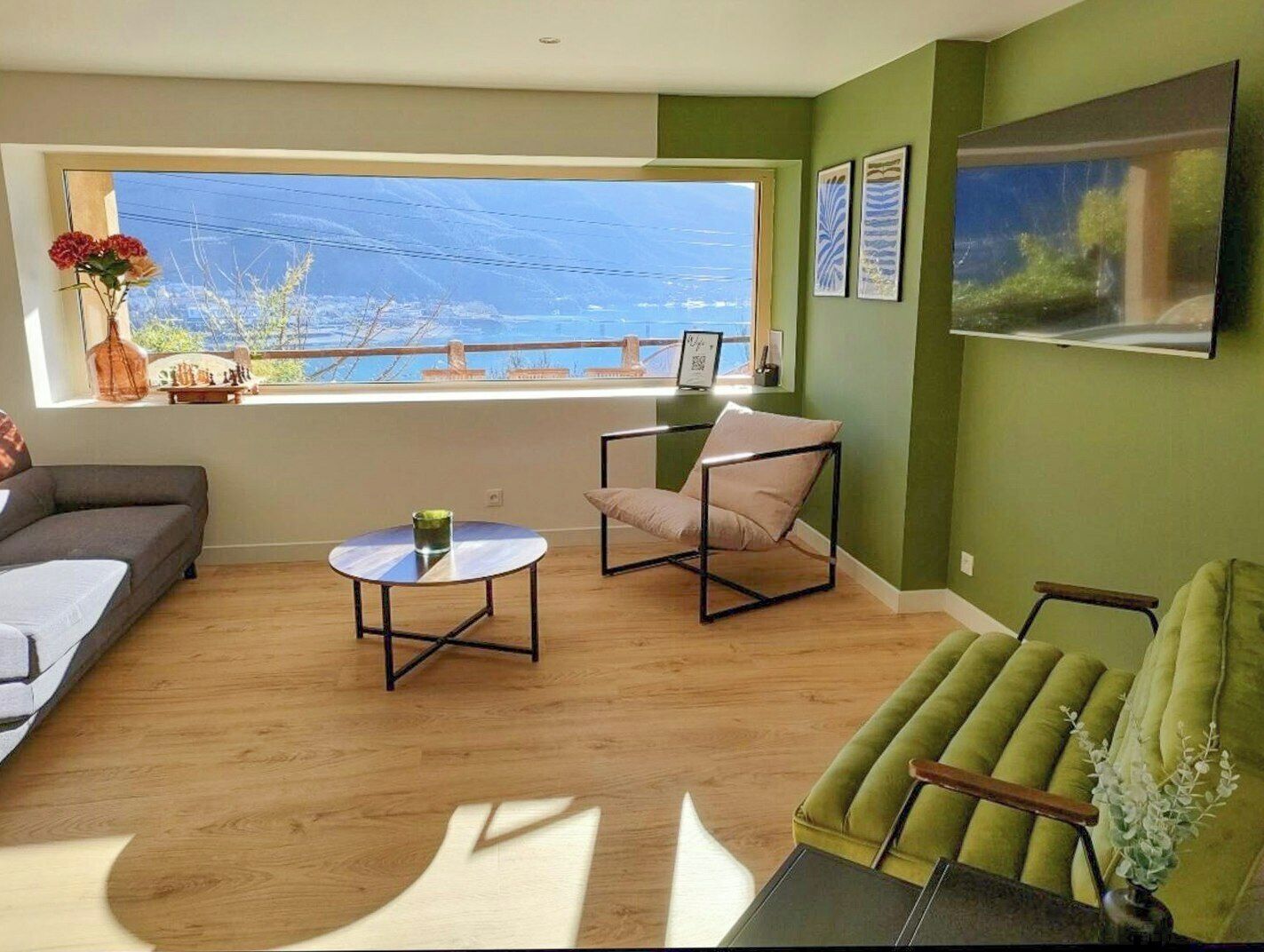 A modern living room with a large window, a sofa, a chair, and a table.