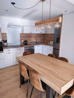 Eine moderne Küche mit einem Holztisch, Stühlen und Pendelleuchten.