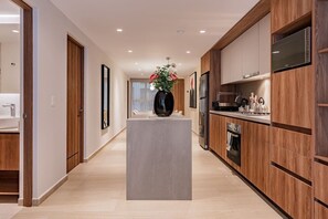 Eine moderne Küche mit Holzausstattung, einer Kochinsel und einem Edelstahl-Kühlschrank.