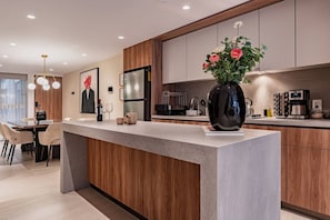 Eine moderne Küche mit Kochinsel, Holzschränken und einer Vase mit Blumen.