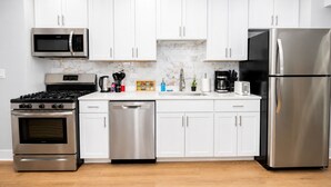 A modern kitchen with white cabinets, stainless steel appliances, and a marble backsplash. - Chicago Edgewater 3BR - 9 Min Walk to Loyola (Chicago)
