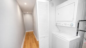 A laundry room with a washing machine, a dryer, and a wooden floor. - Chicago Edgewater 3BR - 9 Min Walk to Loyola (Chicago)