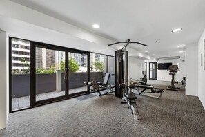 Ein Fitnessstudio mit Trainingsgeräten, großen Fenstern und Blick auf Gebäude.