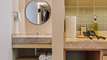 A modern bathroom with a round mirror, a sink, and a toilet.