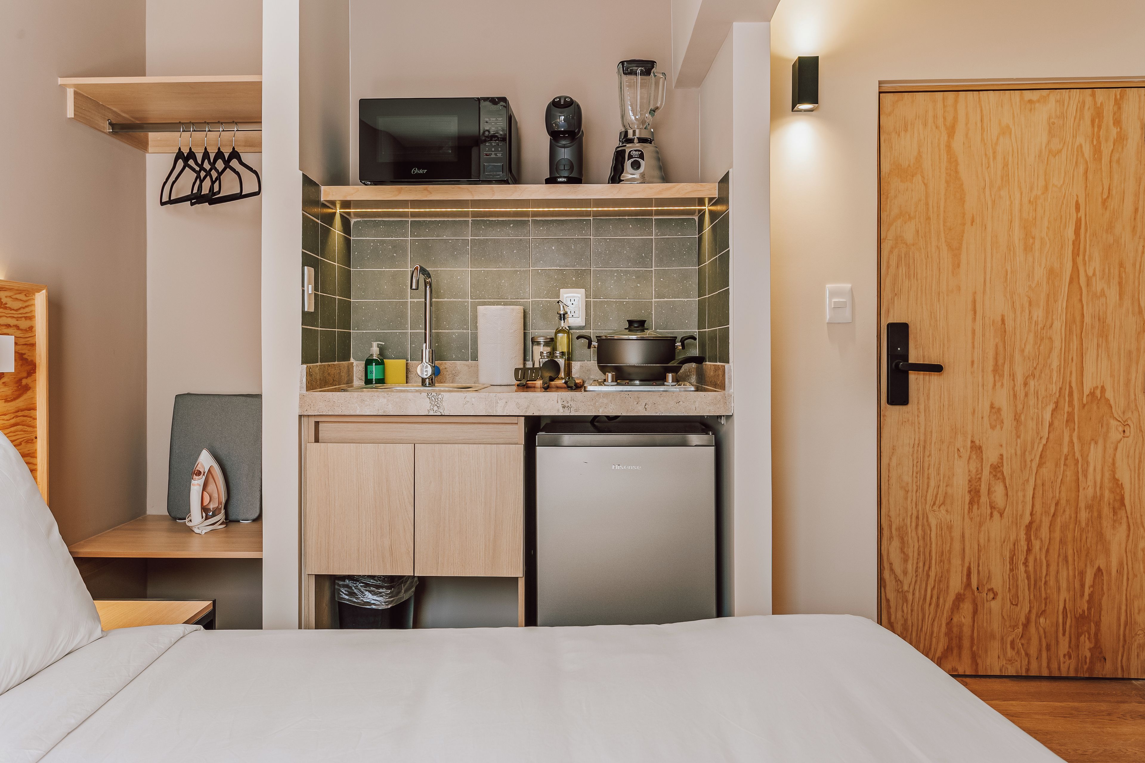A compact kitchenette with a microwave, coffee maker, blender, and a small stove.