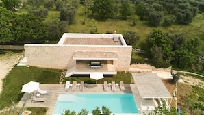A modern villa with a swimming pool, outdoor seating, and a stone facade. - Villa Aurora - Ostuni (Ostuni)