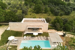 Eine moderne Villa mit Swimmingpool, Sitzgelegenheiten im Freien und einer Steinfassade.