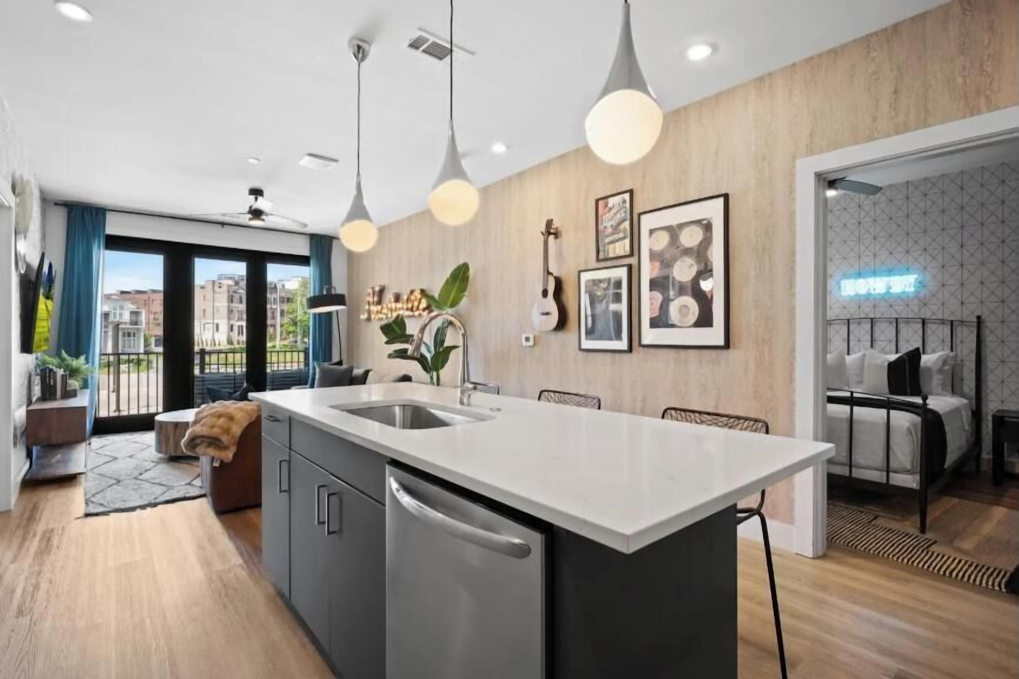 A modern kitchen with a central island, pendant lighting, and a view of the city.