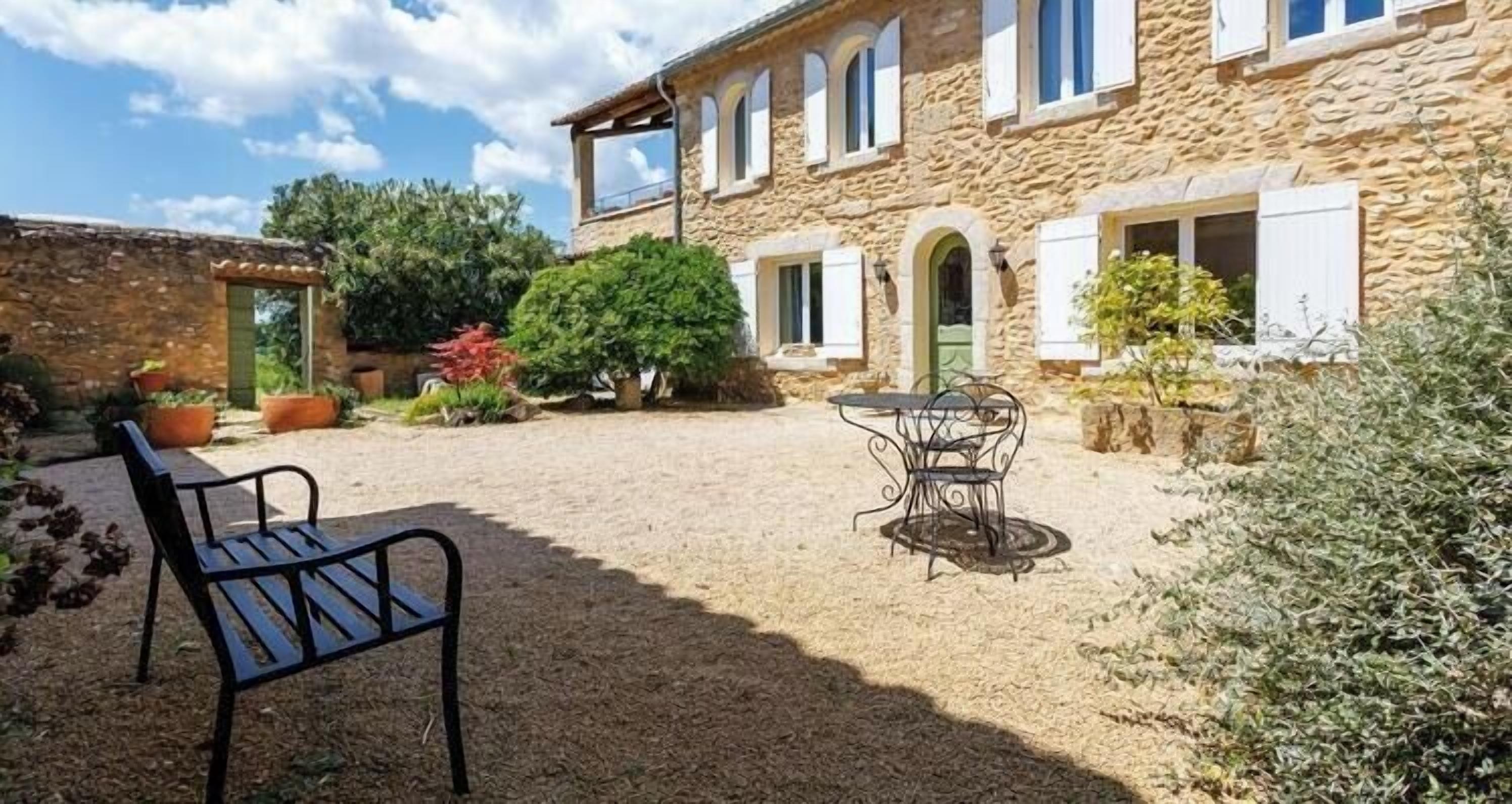 A stone building with a courtyard, a bench, and a table.