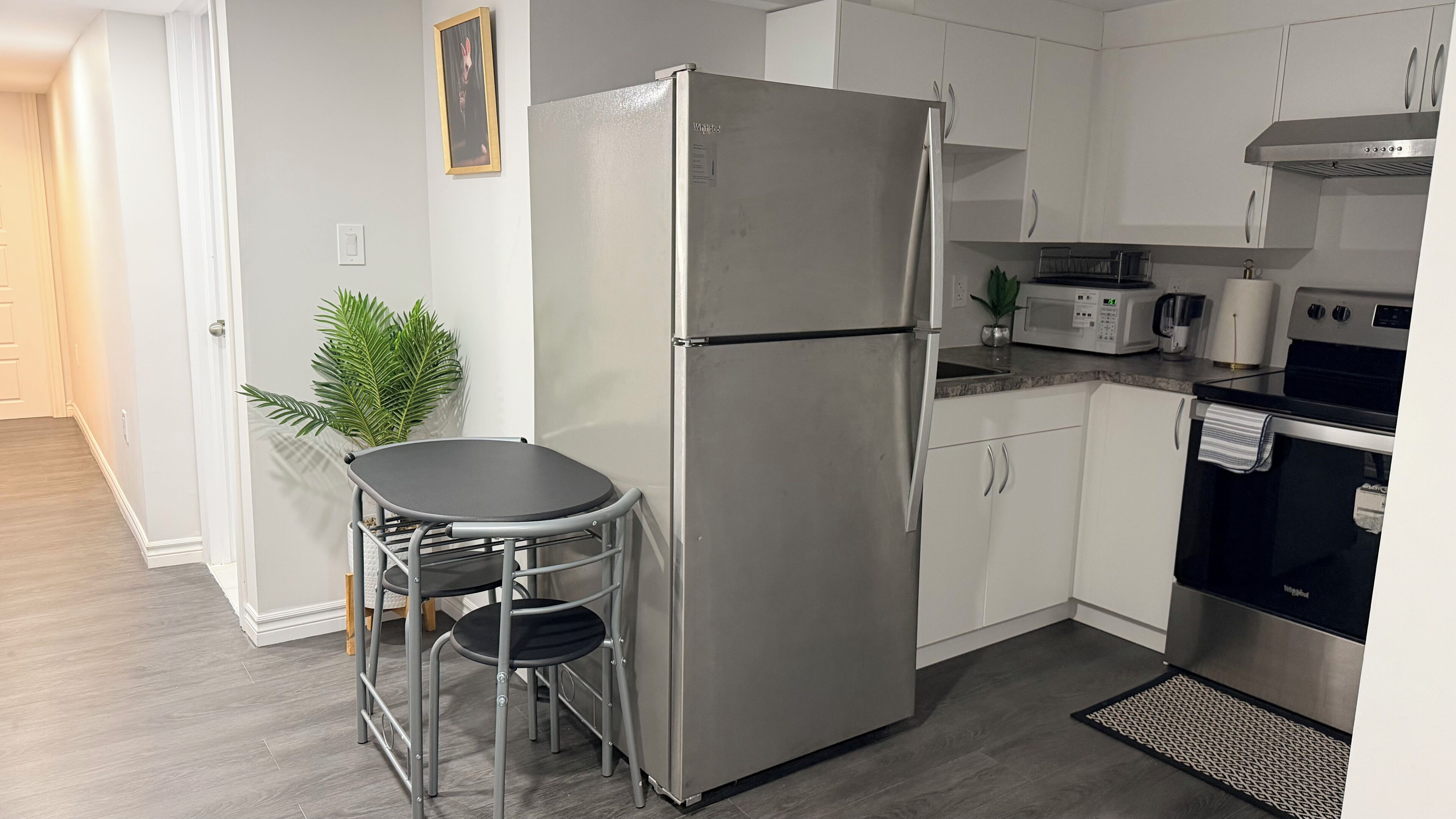 A compact kitchen with a refrigerator, microwave, stove, and a small dining area with a table and chairs.