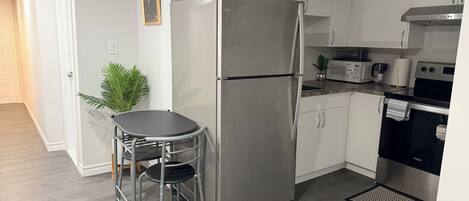 A compact kitchen with a refrigerator, microwave, stove, and a small dining area with a table and chairs.