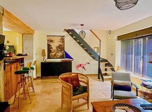 Ein Wohnzimmer mit Treppe, Essbereich und Bar.