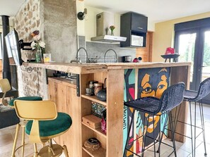 Eine Küche mit Steinwand, Mikrowelle, Spüle und einer Bar mit Stühlen.