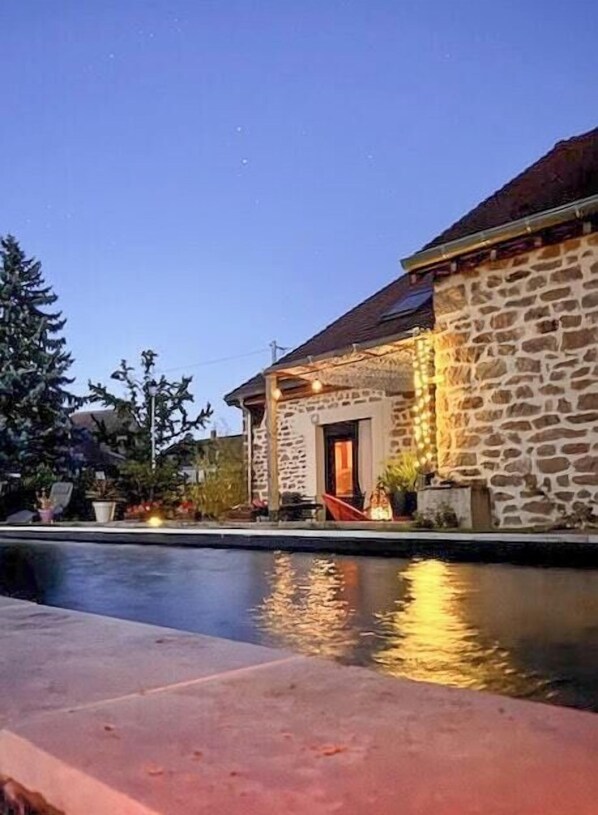 Ein Steinhaus mit einem Pool davor.