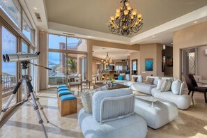 A spacious living area with a large sofa, a coffee table, and a tripod with a camera.