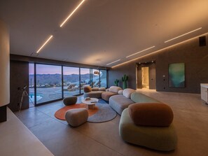 Ein modernes Wohnzimmer mit großem Fenster, Pool und Bergblick.