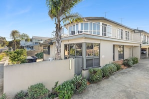 A modern two-story house with a balcony, a garage, and a well-maintained garden. - Sea View Steps to Central Esplanade Pet Friendly (Torquay)