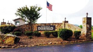 A stone wall with a sign reading 'DEERFIELD' and an American flag. - Perfect Norris Lake 2Br condo in Deerfield Resort with amazing lake views! (LaFollette)