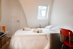 Ein Schlafzimmer mit einem Bett, einem Sessel, einem Fenster und einer Tür.