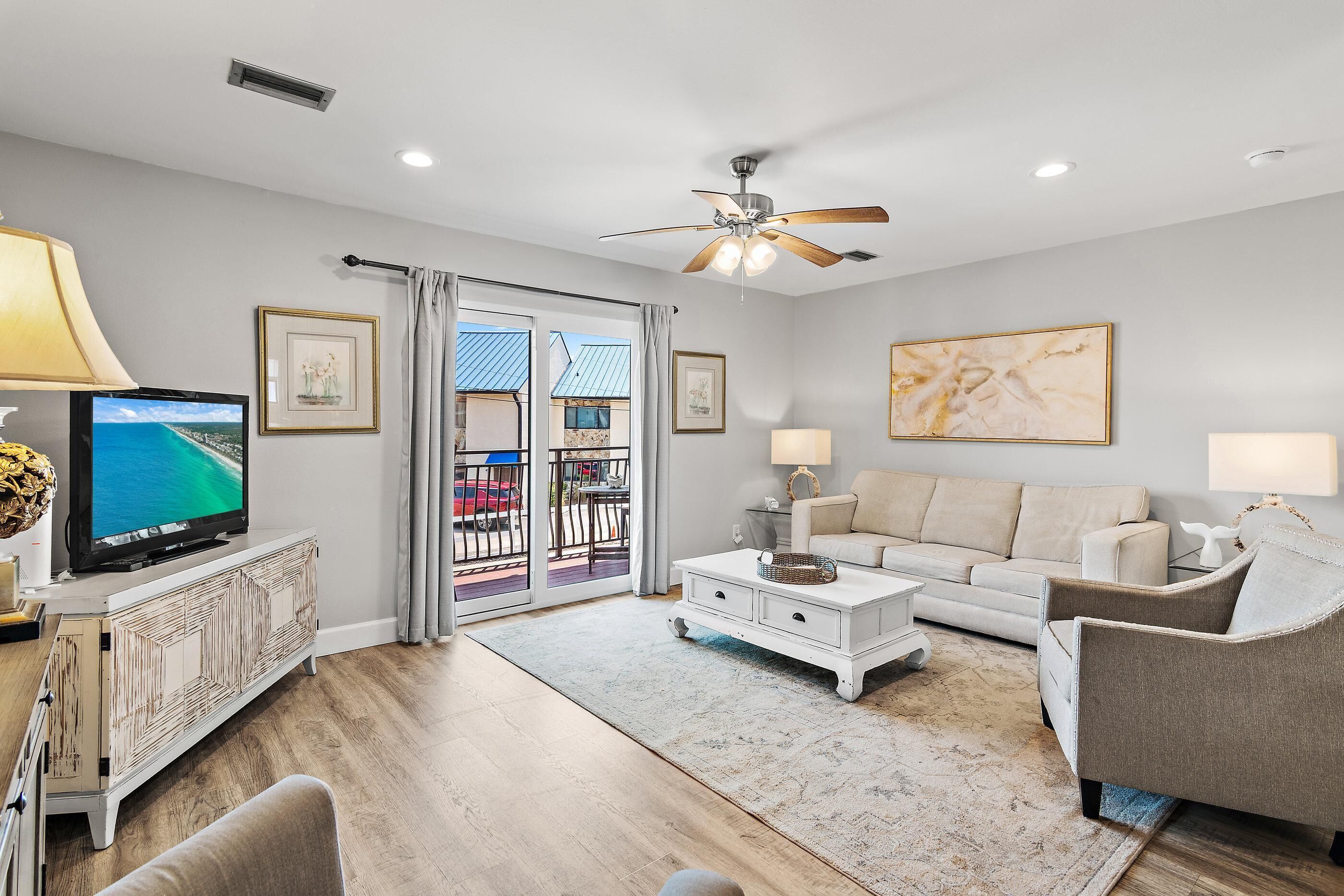 A living room with a television, sofa, armchair, and a ceiling fan.
