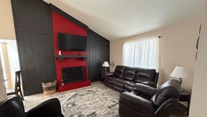 Un salon avec une cheminée rouge, un canapé en cuir et un tapis à motifs.