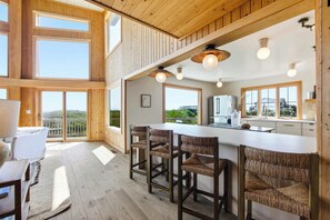 Eine moderne Küche mit Barbereich, Holzboden und großen Fenstern.