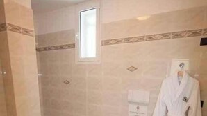 Un bagno con una vasca, un bidet, un WC e un accappatoio appeso al muro.